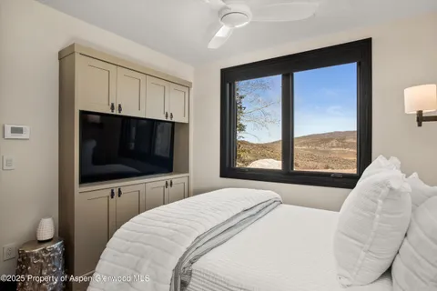 a bedroom with a large bed and a flat tv screen on dresser
