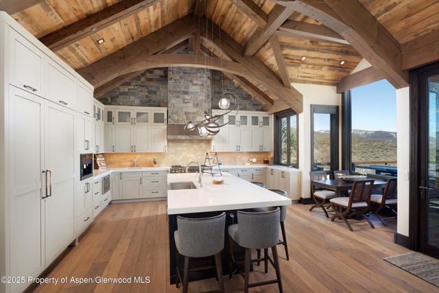 a dining room with wooden floor a chandelier a wooden table and chairs