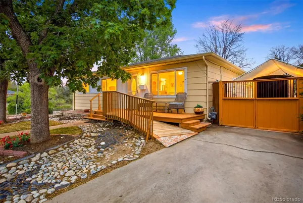 a view of a house with a large tree and wooden fence