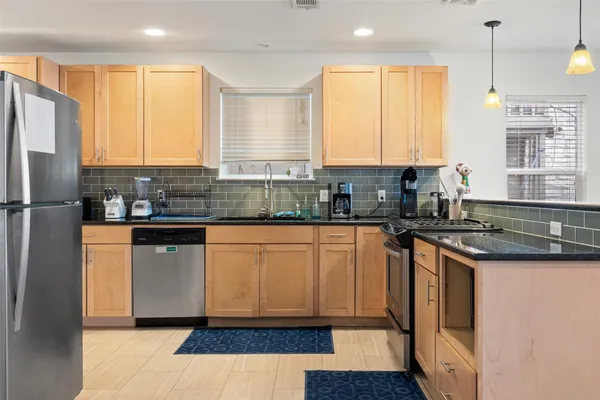a kitchen with stainless steel appliances granite countertop a refrigerator a sink a stove a microwave and island