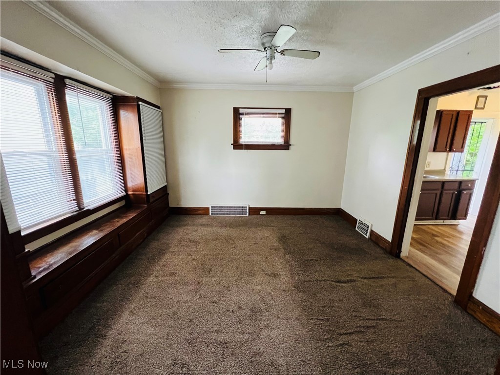 968 Whitby Road Cleveland Heights, OH 44112 - Photo 4 of 19 Spare room with healthy amount of natural light, dark colored carpet, crown molding, a textured ceiling, and ceiling fan