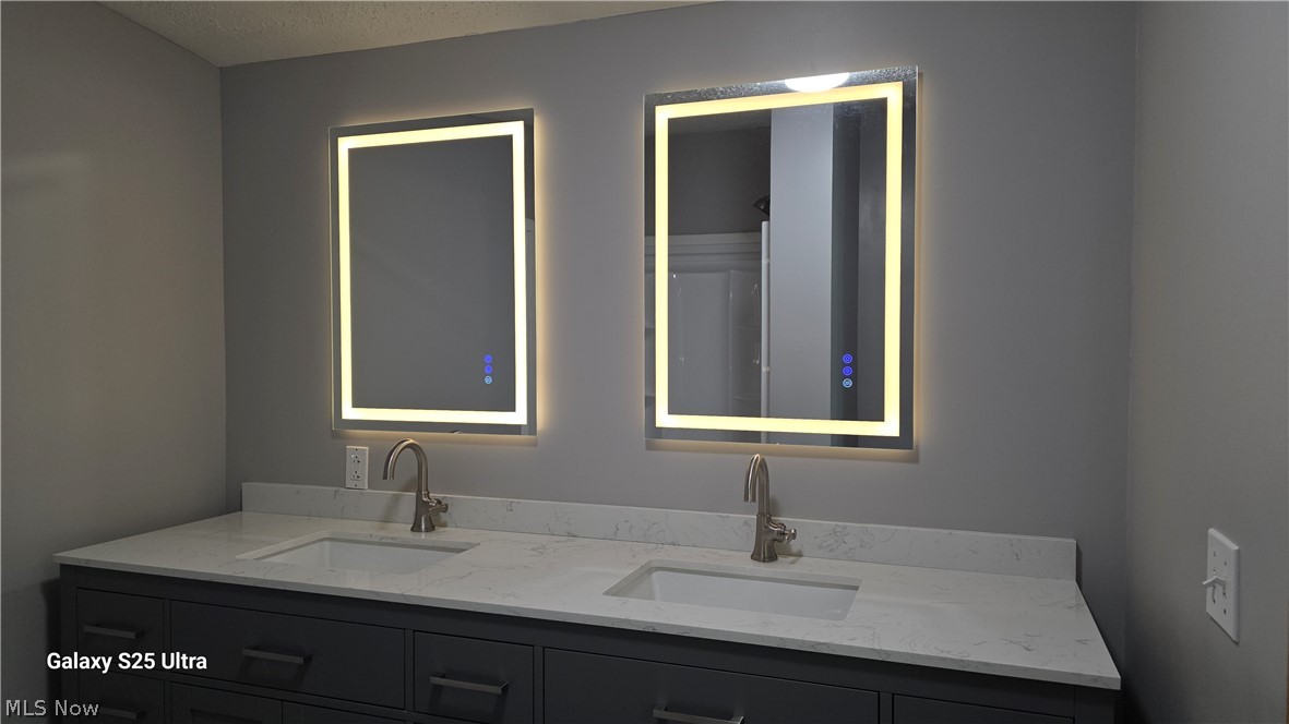 294 Twp 150 Road Sullivan, OH 44880 - Photo 30 of 39 Dual vanity featuring two illuminated rectangular mirrors, individual undermount sinks, and brushed nickel faucets