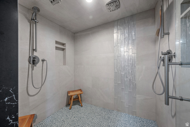 4221 Juniper Circle Alpine, UT 84004 - Photo 34 of 66 Spacious shower featuring a pebble tile floor, light-toned wall tiling, dual showerheads, and an integrated wall niche