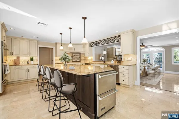 a kitchen with stainless steel appliances kitchen island granite countertop a table chairs and a sink