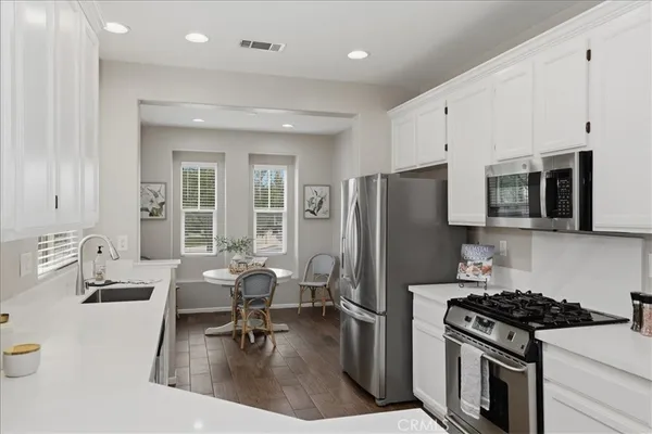 a kitchen with stainless steel appliances granite countertop a stove a refrigerator a sink a table and chairs