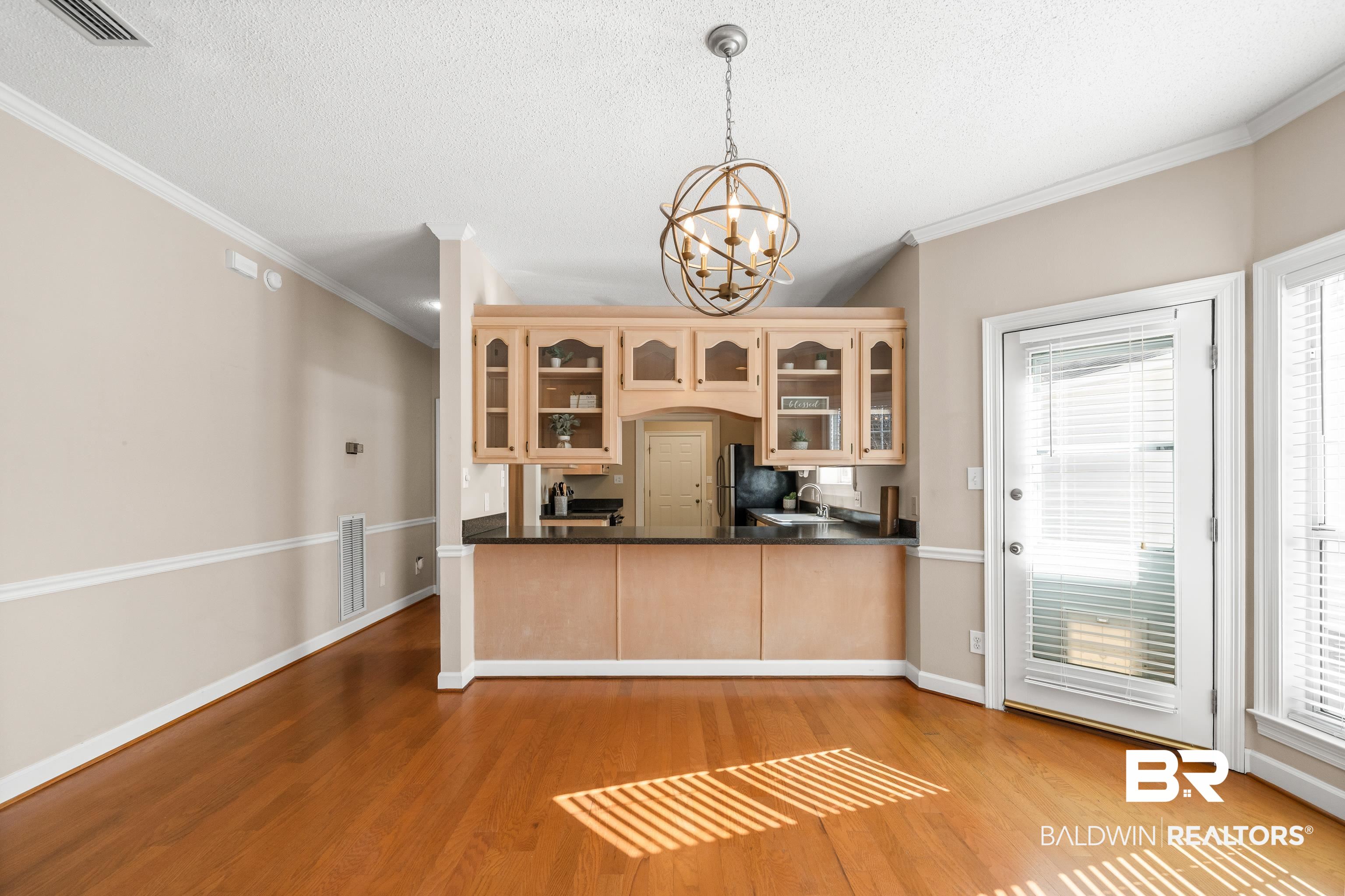 27 Cottage Drive Fairhope, AL 36532 - Photo 9 of 33 Kitchen featuring a peninsula, hanging light fixtures, dark countertops, a textured ceiling, and glass insert cabinets