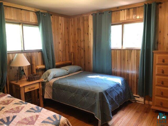 444 Fernberg Road, Unit 11 Ely, MN 55731 - Photo 4 of 19 Bedroom featuring wooden walls, multiple windows, and wood finished floors