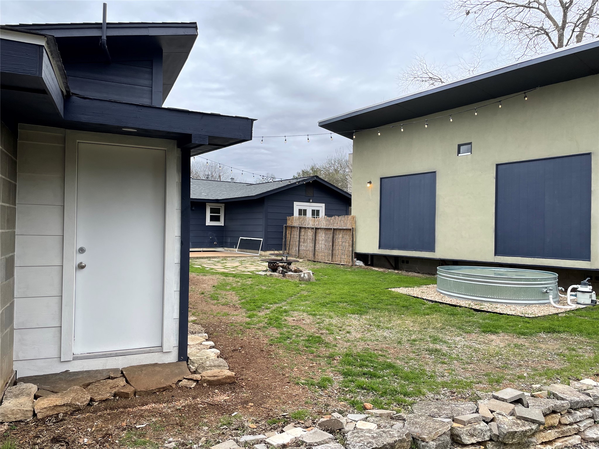 4619 Jinx Avenue, Unit A Austin, TX 78745 - Photo 18 of 21 Enclosed backyard featuring two distinct structures, a gravel-surrounded stock tank, and a fire pit area