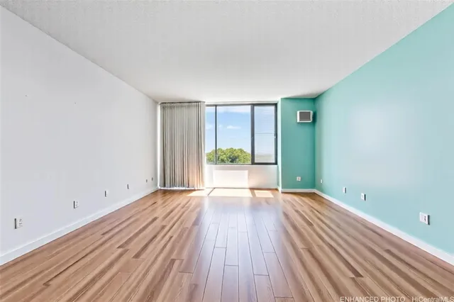 a view of an empty room with wooden floor and a window