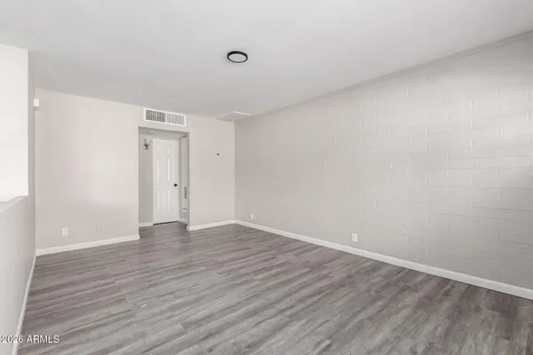a view of an empty room with wooden floor and closet