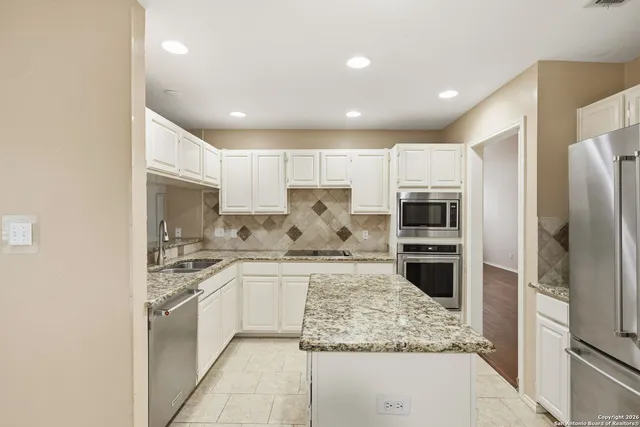 a kitchen with stainless steel appliances kitchen island granite countertop a stove refrigerator and cabinets