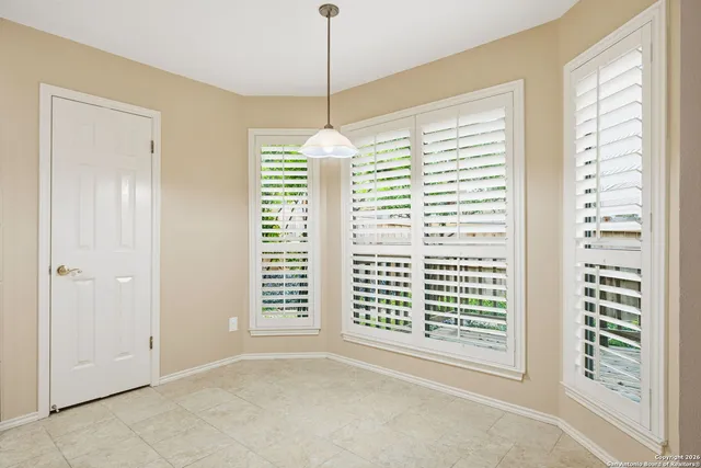 a view of an empty room with windows and chandelier