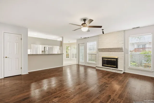 a view of an empty room with wooden floor fireplace and a window