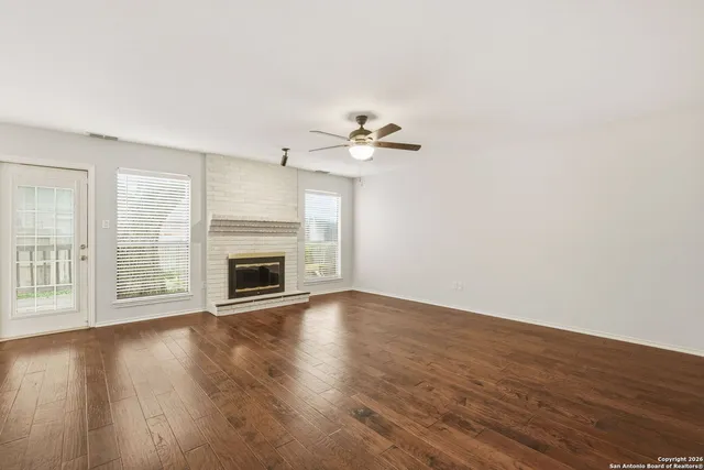 a view of an empty room with wooden floor and a fireplace