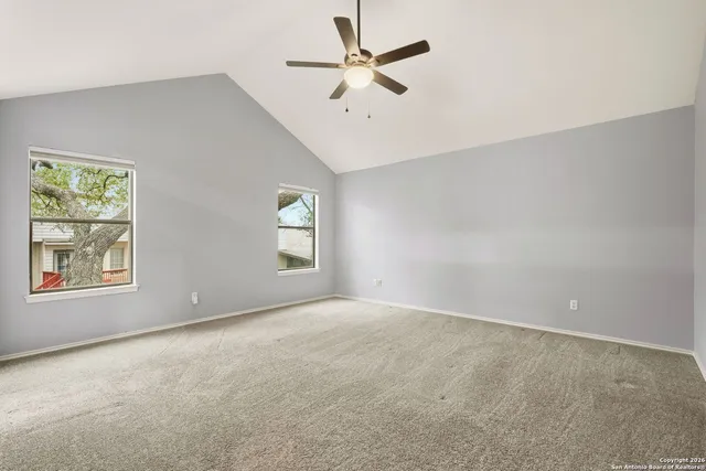 an empty room with windows and fan