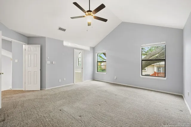 an empty room with windows and fan