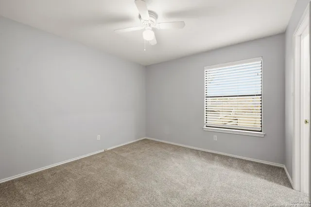 an empty room with a window and a fan