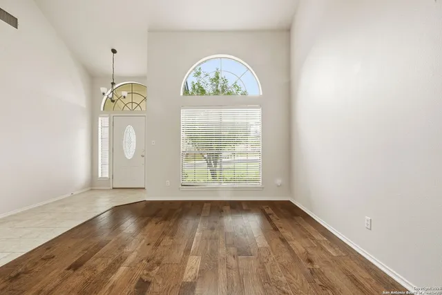 an empty room with wooden floor windows and