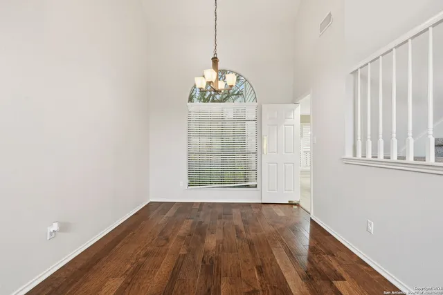 a big room with wooden floor a ceiling fan and windows