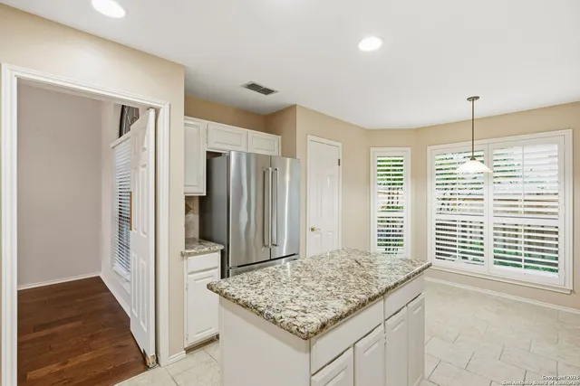 a view of kitchen island a refrigerator sink and wooden floor