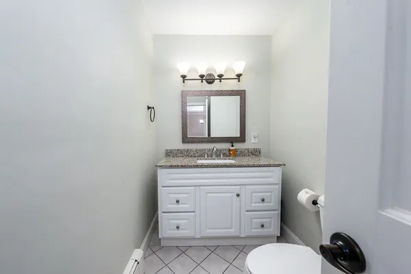 a bathroom with a granite countertop toilet sink and mirror