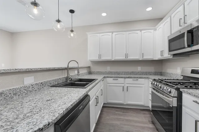 a kitchen with granite countertop a sink a stove and cabinets