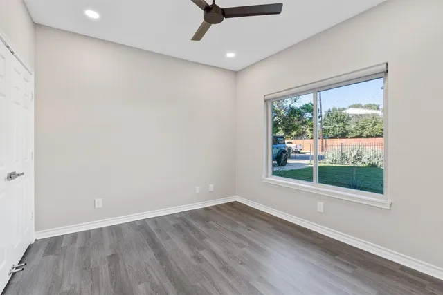 an empty room with wooden floor and windows