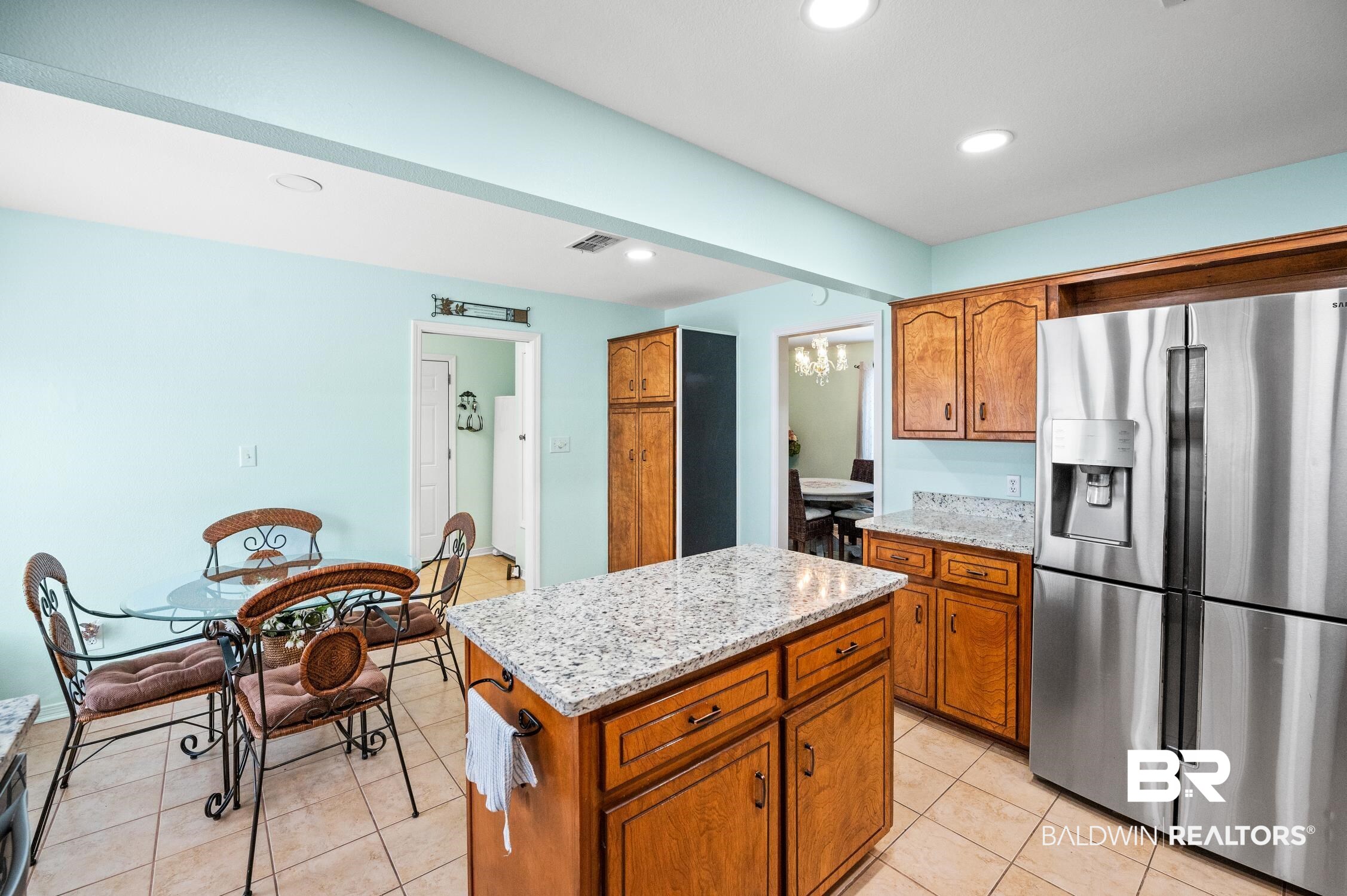2553 Santa Rosa Drive Lillian, AL 36549 - Photo 16 of 51 Kitchen with light tile patterned floors, a kitchen island, visible vents, stainless steel refrigerator with ice dispenser, and brown cabinets