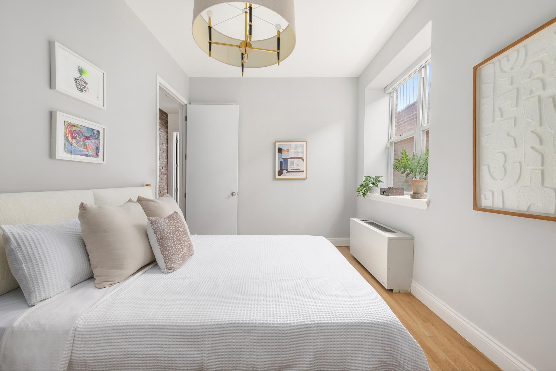 229 West 116th Street, Unit 2B Manhattan, NY 10026 - Photo 7 of 18 a bedroom with a large bed and a chandelier
