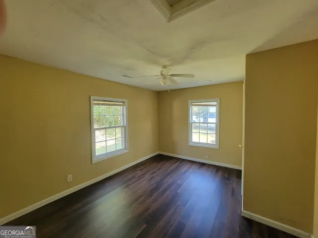 a view of an empty room with a window and wooden floor