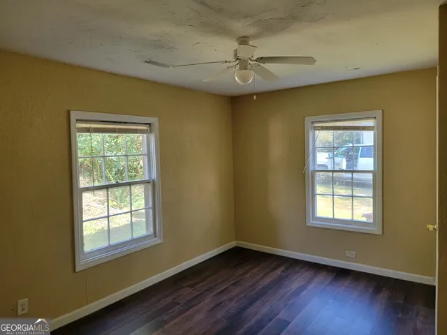 an empty room with windows and fan