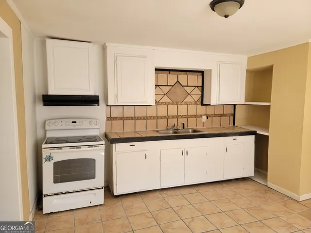 a kitchen with granite countertop white cabinets and white appliances
