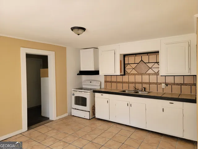 a kitchen with granite countertop white cabinets and white appliances