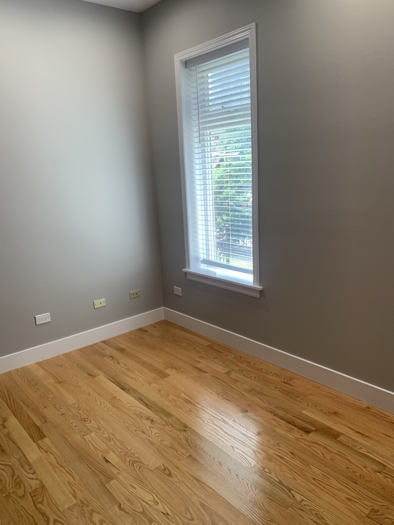 1303 West Flournoy Street, Unit 1F Chicago, IL 60607 - Photo 11 of 15 an empty room with wooden floor and windows