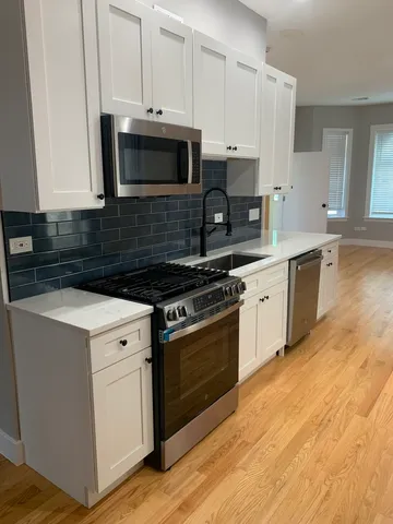 a kitchen with stainless steel appliances white cabinets and a stove top oven