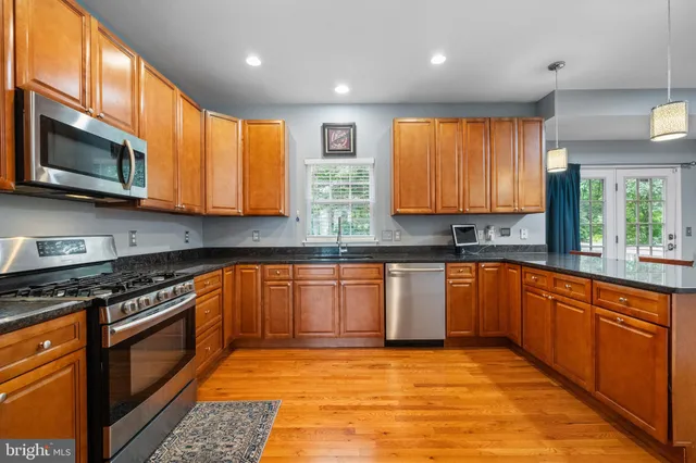 a kitchen with stainless steel appliances granite countertop wooden cabinets a stove top oven a sink and dishwasher