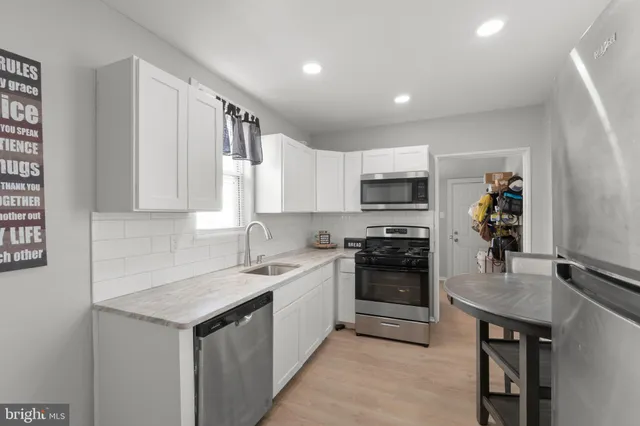 a kitchen with stainless steel appliances a table chairs microwave and refrigerator