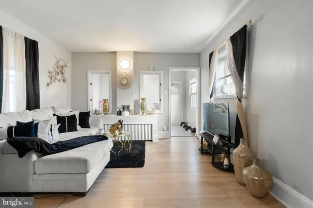 a living room with furniture and a large mirror next to a window