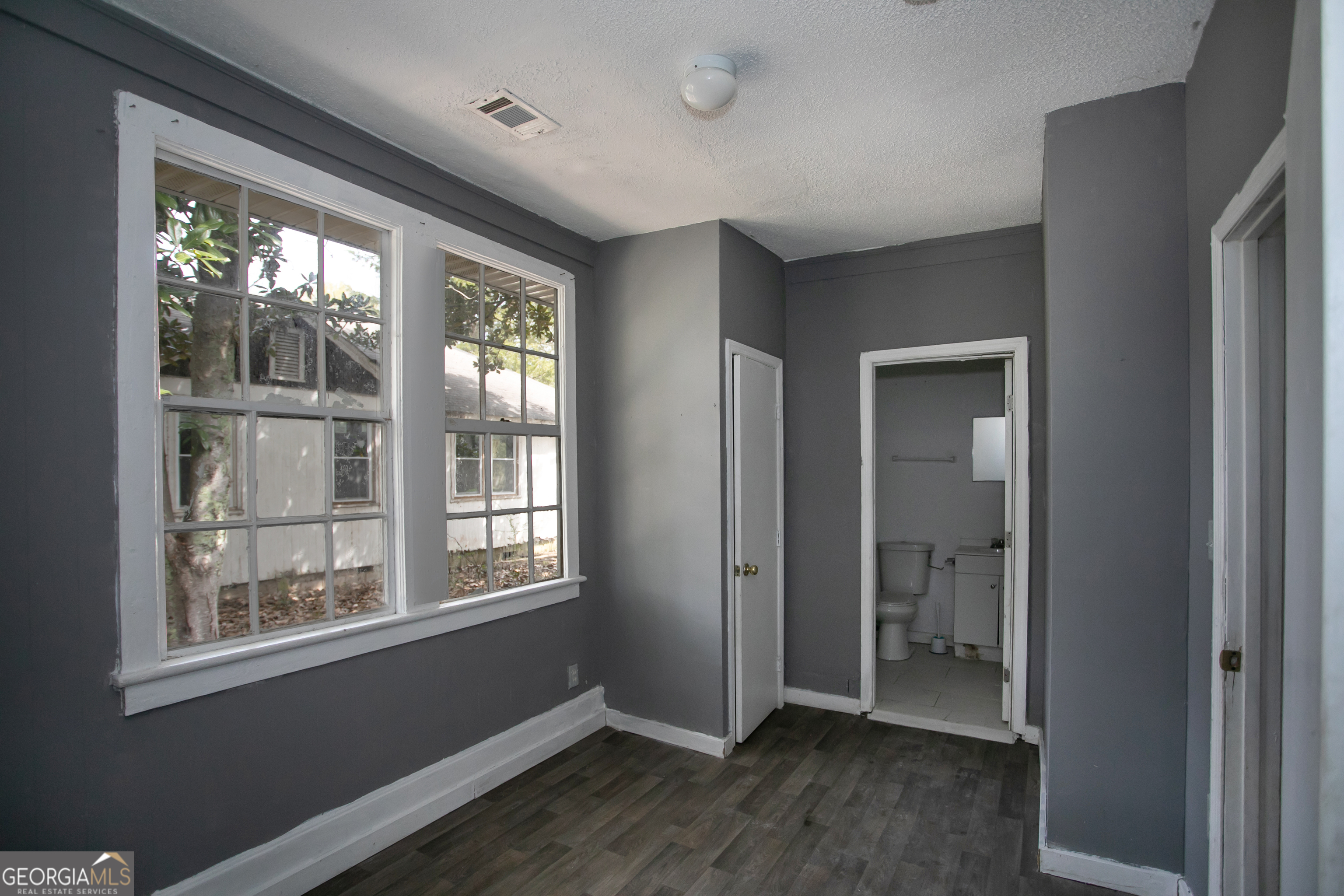 402 Boulevard Street Fort Valley, GA 31030 - Photo 7 of 10 an empty room with wooden floor and windows