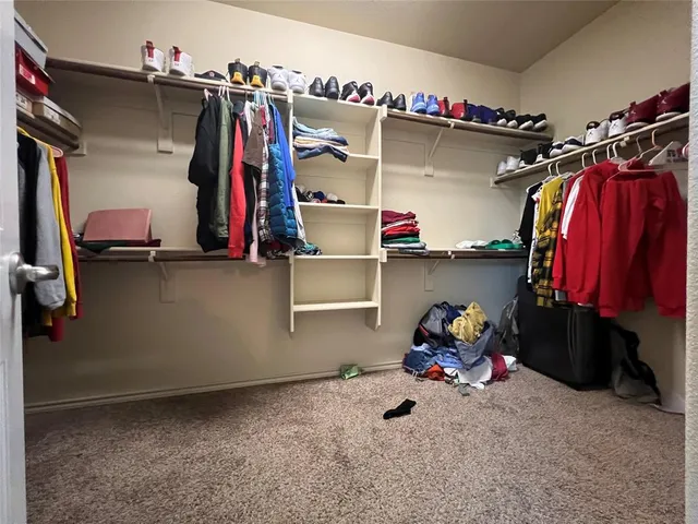 a view of walk in closet with clothes and shoes