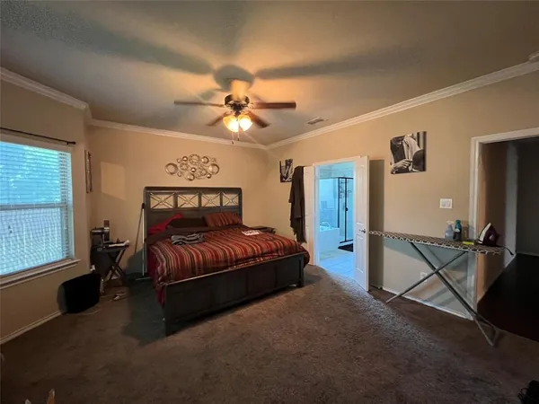 a spacious bedroom with a bed and a large window with a flat tv screen on the dresser