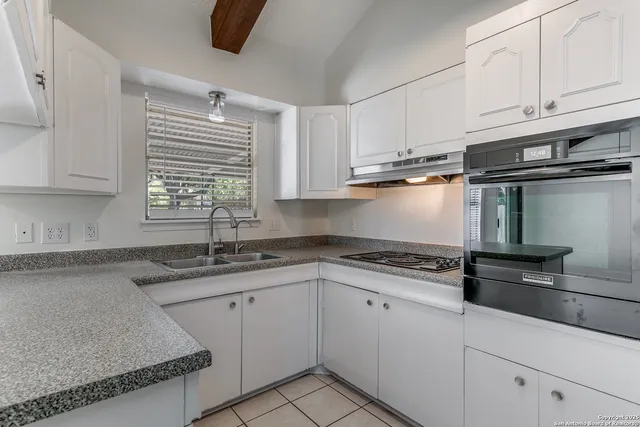 a kitchen with granite countertop a sink stainless steel appliances and cabinets