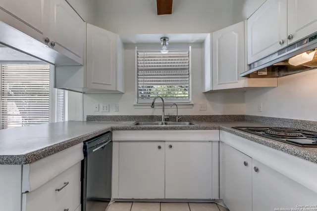 a kitchen with granite countertop a sink a stove and cabinets