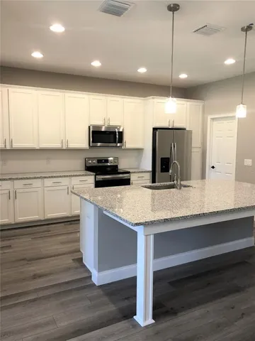 a kitchen with kitchen island a counter space a sink appliances and cabinets