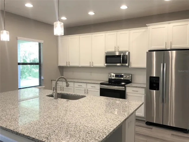 a kitchen with kitchen island granite countertop a sink stove and refrigerator