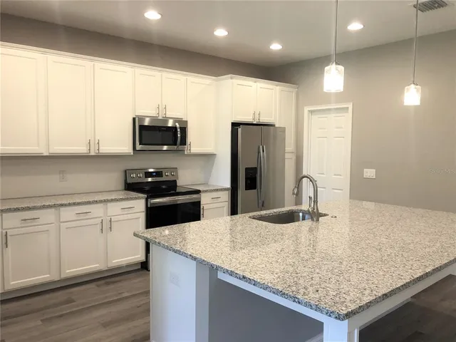 a kitchen with kitchen island granite countertop a sink counter space and refrigerator