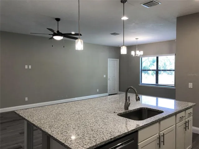 a kitchen with a granite countertop sink vanity and chandelier