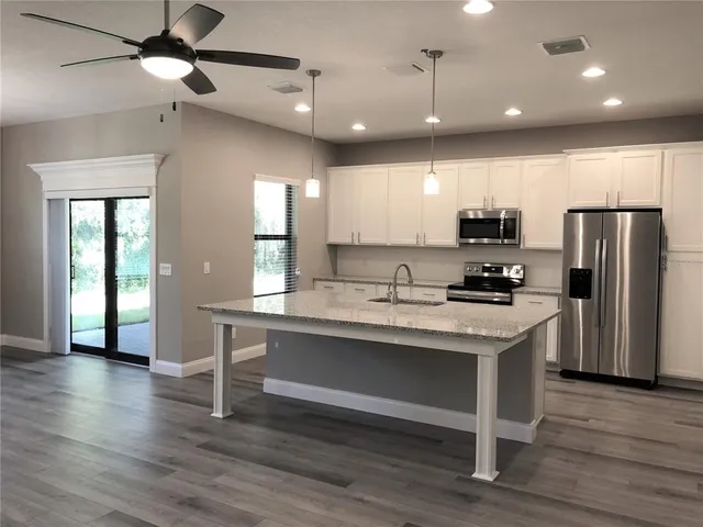 a kitchen with kitchen island white cabinets and stainless steel appliances