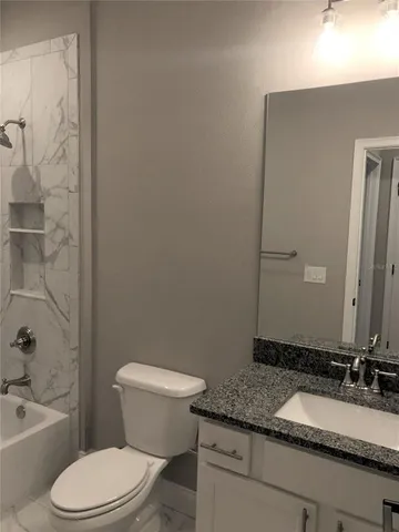a bathroom with a granite countertop toilet sink and mirror