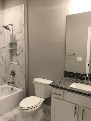a bathroom with a granite countertop toilet a sink and a bathtub